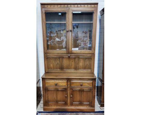 A modern Ercol medium elm full height side/display cabinet with 2 glazed doors, fall front secretaire section, 2 cupboards an