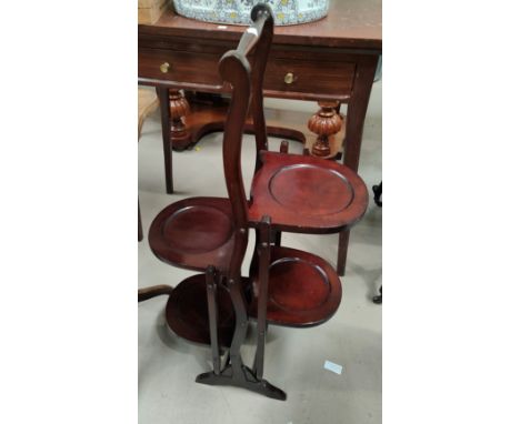 An early 20th century bevelled edge wall mirror in oval mahogany effect frame; a 4 height folding cake stand 