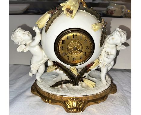 A 19th century Moores porcelain mantel clock, supported by 2 cherubs with flowering cactus mounts, gilt dial and French balan
