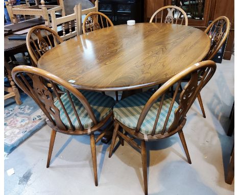 A modern Ercol medium elm dining suite comprising large oval table on central pedestal, and 6 wheel back chairs 