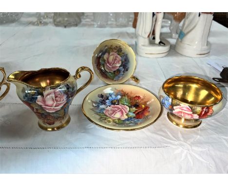 An Aynsley enameled over transfer   tea cup and saucer, milk jug and sugar bowl, gilt flowers, signed L A Bailey.   The piece