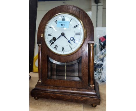 An early 20th century circular top oak mantle clock with side pillars and striking movement