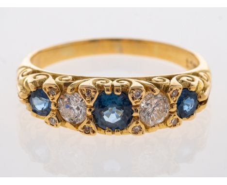 A sapphire & diamond five stone ring in carved 18ct yellow gold mount, sapphires are mid blue, diamonds brilliant cut with di