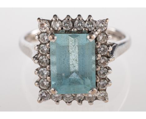 An aquamarine and diamond ring, the rectangular cut aquamarine claw set within a surround of brilliant cut diamonds, stamped 