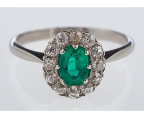 An emerald & diamond ring, the oval emerald of fine colour, within a border of old cut diamonds, emerald estimated at 0.65 ca