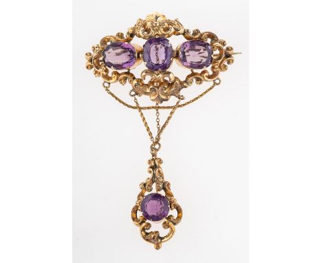A Victorian amethyst brooch, circa 1870, the openwork scrolled brooch with engraved foliate detail set with three cushion cut
