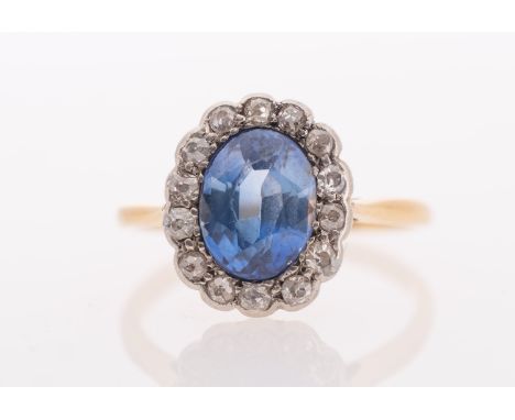 A sapphire & diamond ring, the oval faceted sapphire of good colour measuring 8.5 x 6.5 mm, set in a border of old cut diamon
