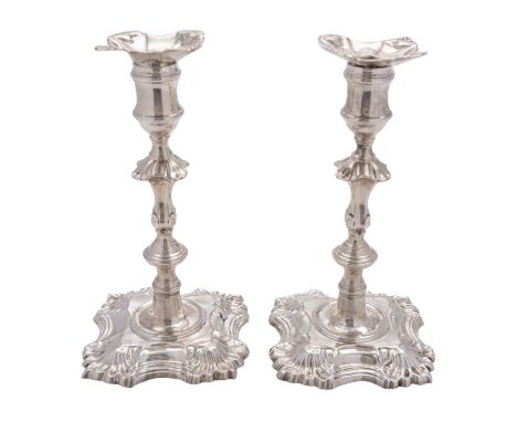 A pair of late George II cast silver candlesticks by John Cafe, London 1753, shaped square with shells at the angles, with un