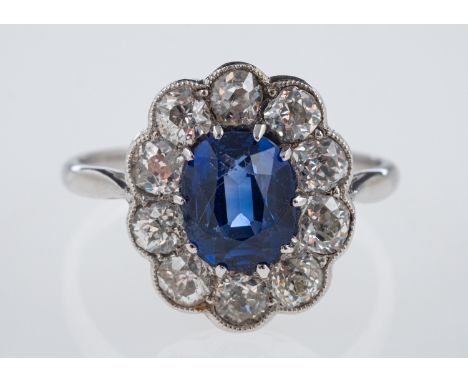 A sapphire & diamond ring, the oval faceted sapphire of  around 1.75 carats, within a border of old cut diamonds in millgrain