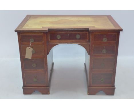 An Edwardian satinwood inlaid mahogany breakfront kneehole desk with an arrangement of nine drawers and raised on carved brac
