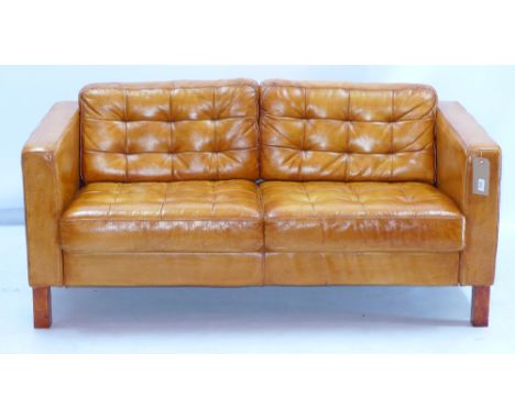 A contemporary tan leather two seater sofa, having buttoned style back and seat, raised on square section supports H 70 x W 1