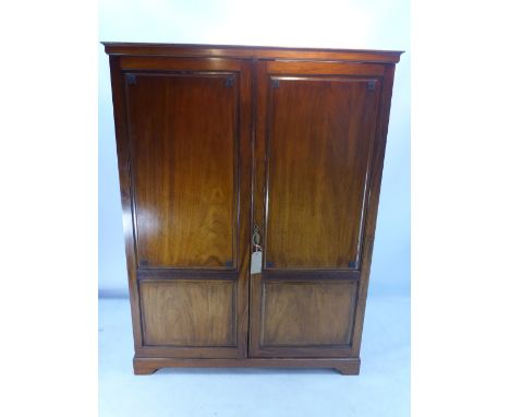An Edwardian mahogany wardrobe with two doors enclosing shelves, drawers and rail and raised on bracket feet, H 174 x W 132 x