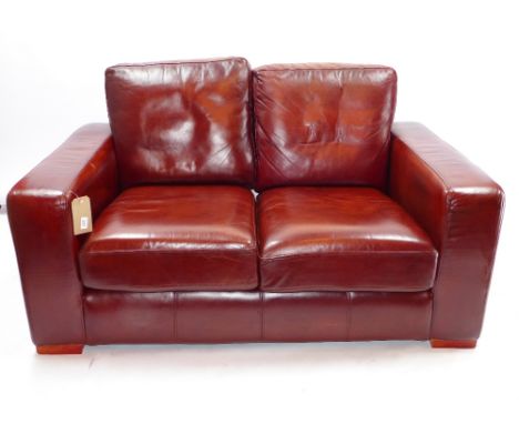 A contemporary Thomas Lloyd burgundy leather two seater sofa of angular form H 59 x W 155 x D 98cm 