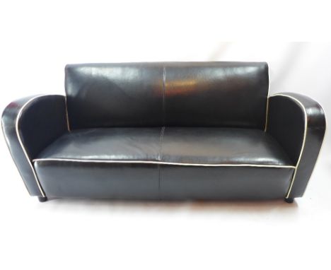 An Art Deco style black leather two seater sofa with white piping and raised on bun feet, H 80 x W 174 x D 80cm 