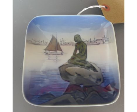 A Royal Copenhagen ceramic square dish decorated with a nude on a rocky outcrop with boats in the distance, stamped with thre
