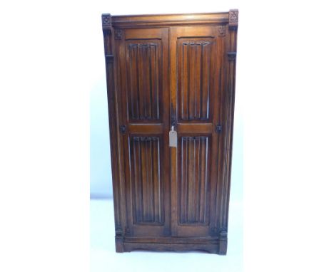 A Gothic style oak hall cupboard with two doors enclosing shelves and raised on carved bracket feet, H 183 x W 93 x D 45cm 