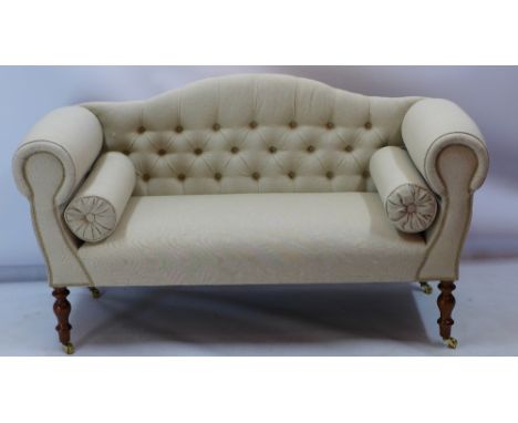 A Victorian style camel back sofa upholstered in a stone linen raised on turned legs and castors H 77 x W 137 x D 55cm 