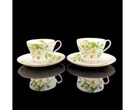 Vintage white bone china with white flowers and bright green leaves, gilt rims. Two tea cups and two saucers. Windsor shape. 