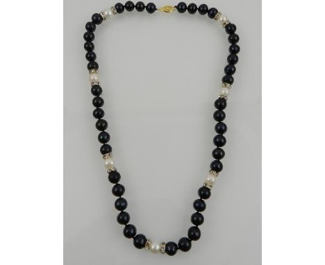 A South Sea black and white pearl necklace, interspersed with beads of channel set cubic zirconia, with a 14 carat yellow gol