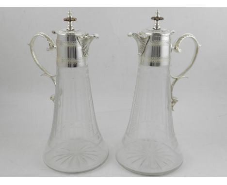 A pair of cut glass claret jugs, having silver plate handles and lids. H.30cm