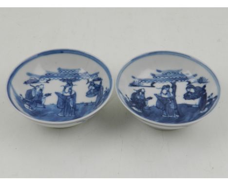 A pair of Chinese late Qing period (1644-1912) miniature blue and white shallow bowls, both decorated centrally with nobleman