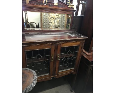 An Edwardian display cabinet with a mirrored back above lead light glazed doors on square legs.