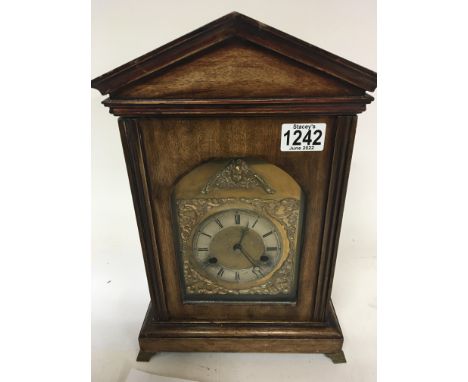 An Edwardian walnut mantel clock with a brass dial and silver chapter ring.