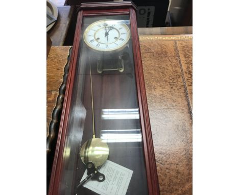 A reproduction wall clock with visible pendulum.