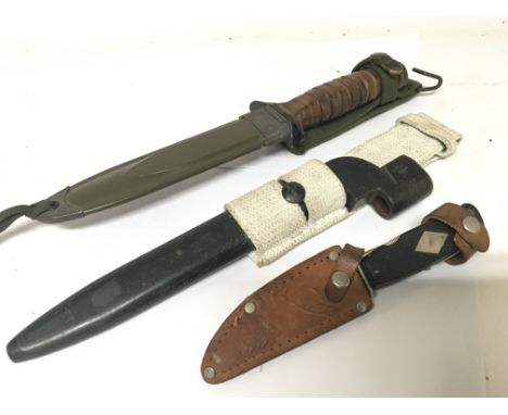 A military knife in a green metal scabbard a small bayonet and a small multi purpose knife in a leather scabbard. (3)