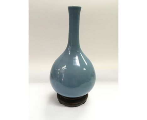 A powder blue bottle vase raised on a hardwood stand, approx 28cm.