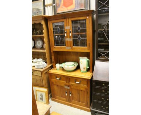 Pine Dresser, the upper section with glass doors above two drawers and two cupboards with iron and ceramic handles, 98cms wid
