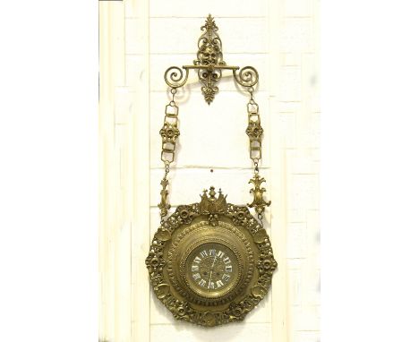 A late 19th century French brass cased hanging wall clock with eight day movement striking on a gong, the embossed dial inset