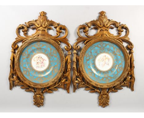 A GOOD PAIR OF SEVRES DESIGN CIRCULAR PLATES in pierced gilt frames, blue and gilt borders, painted with cupids. 10.5i s diam