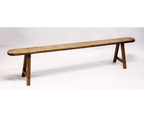 A 19TH CENTURY ELM TRESTLE BENCH, single plank construction, rounded ends on stretchered square legs. 6ft 7ins long x 7ft wid