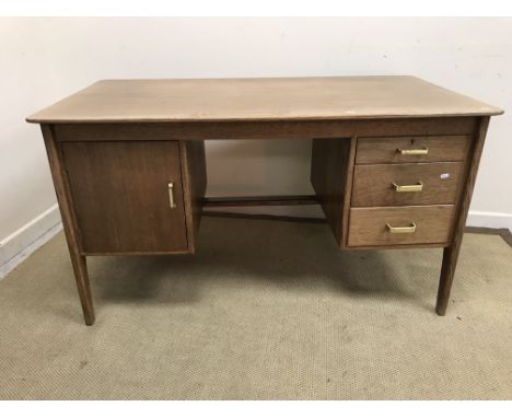 A mid 20th Century Gordon Russell oak office desk, the plain top above a bank of three drawers with brass handles to one side