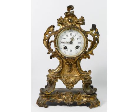 A French mantel clock in a gilt metal rococo style body, enamelled dial with Roman numerals, the glazed rear door revealing m