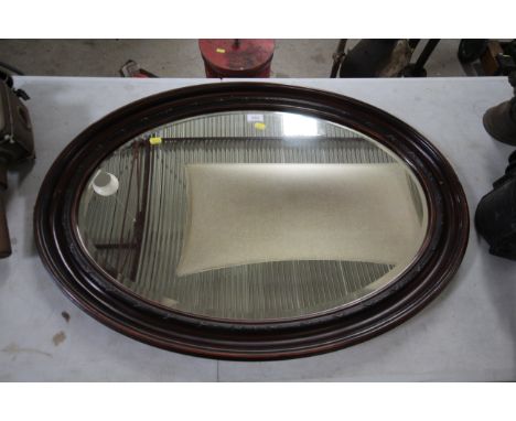 An early 20th Century simulated rosewood framed oval bevel edged wall mirror 