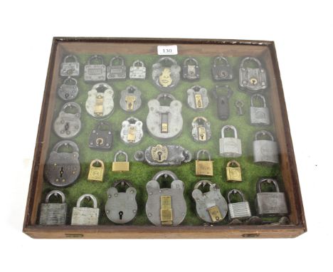A wooden hanging cabinet with examples of 34 vintage padlocks, some with keys 