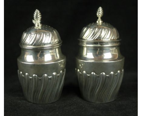 A Victorian pair of silver peppersEmbossed with twist fluted lower bodies, with pierced pull-off lids and twist finials, by H