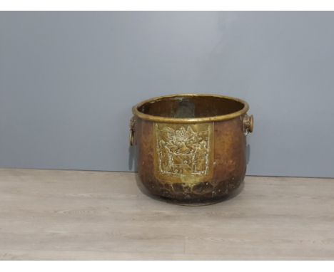 A copper and brass pot with lion head and ring handles