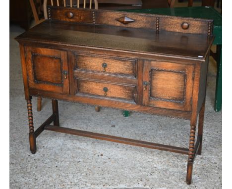 An oak sideboard with two drawers over cupboards, raised on bobbin turned supports united by a centre stretcher, circa 1920's