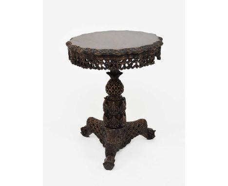 A Burmese carved hardwood tilt-top table, 19th centuryThe circular top with undulating edge, carved in relief with flowerhead