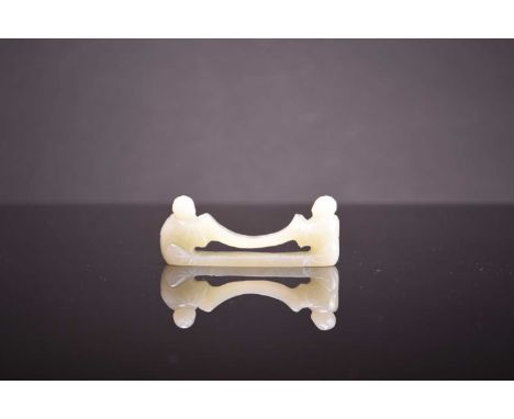 A Chinese pale celadon jade brush rest, late Qing Dynasty Modelled as two Confucian boys kneeling and facing each other, hold