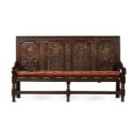 A CARVED OAK FOUR PANEL SETTLE