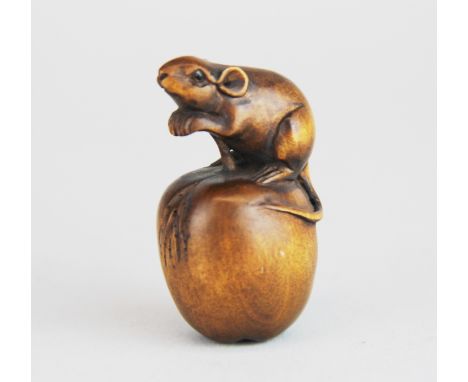 A signed carved fruitwood Netsuke of a mouse sitting on an apple with black onyx eyes, H. 5cm.