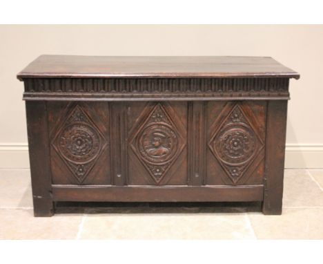A 17th century oak coffer, the hinged cover above a nulled frieze and three panels, the central panel carved with a Romayne r