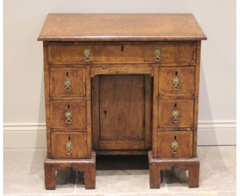 A George II figured walnut kneehole desk, the quarter veneered and crossbanded top with a moulded rim over one long frieze dr