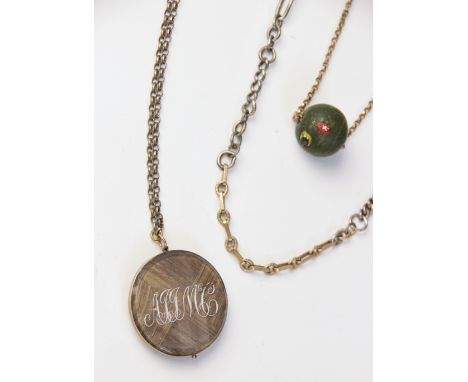 A Victorian memorial pendant, the transparent circular pendant containing braided hair, beaded monogrammed initials to one si
