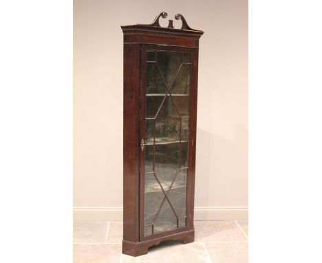 * An Edwardian mahogany freestanding corner display cabinet, with an associated twin swan neck pediment (detached), over a mo