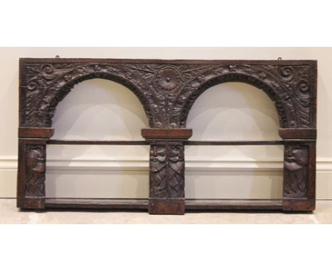 A 17th century and later constructed oak hanging wall shelf, of twin arcaded form, carved in relief with foliate scrolls and 